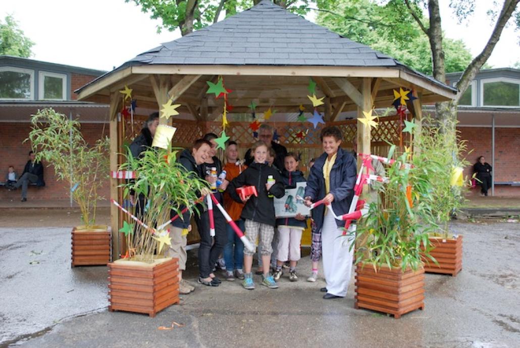 Klassenlehrerin Barbara Rauter (vorne rechts) weiht stolz mit Projekthelfern, Organisatoren und einigen Schülern der 4b das „sternenstrahlende Pausendach“ ein.