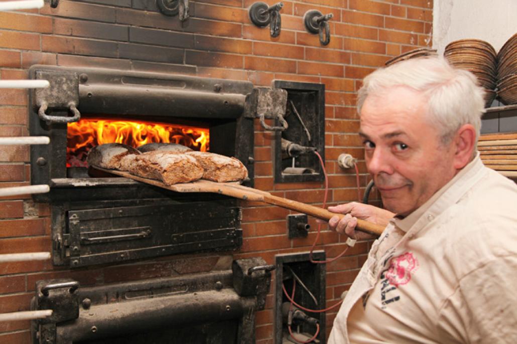 Bäckermeister Heinrich Vorbeck mit fertigen Broten vor dem Holzofen; Foto: Wibke Freund