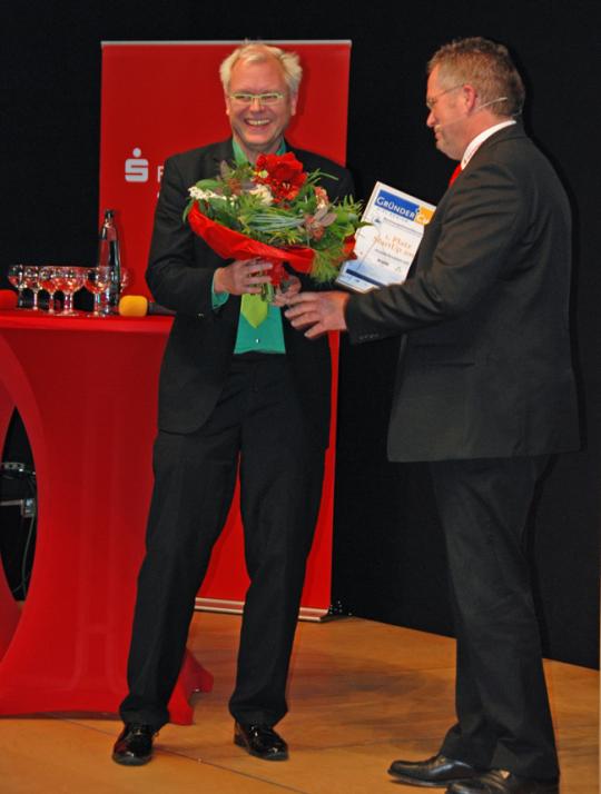 Ralf Reikat, Vertriebsdirektor der Fördesparkasse, gratuliert dem diesjährigen Gewinner, Sven-Hauke Kaerkes von der Musterknaben eG (v.re.)