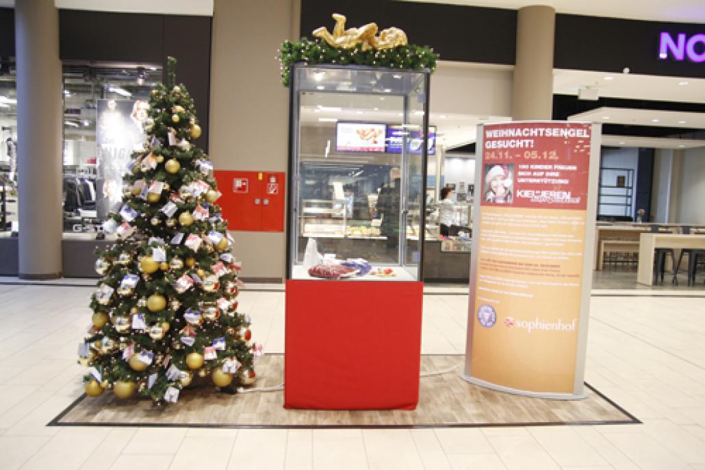 Der Weihnachtsbaum mit den Wunschkärtchen sowie die Vitrine mit den bereits abgegebenen Geschenken stehen im SOPHIENHOF vor Edeka im Erdgeschoss