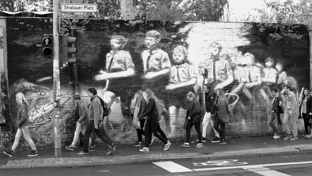 In den Serien Street Art und Found Art setzt Dittloff Personen in Beziehung zu ihrer Umwelt. hier: lässig gekleidete Jugendliche vor einer Wandbemalung, die die marschierende Hitler-Jugend zeigt