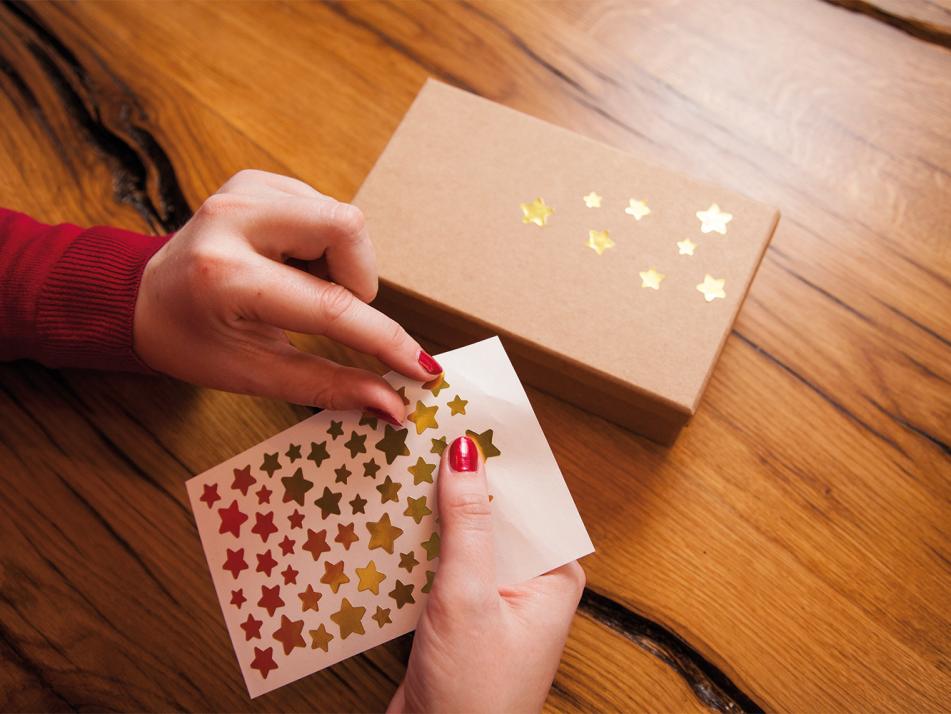 Schritt 2: Sternchenaufkleber auf das eingepackte Geschenk kleben