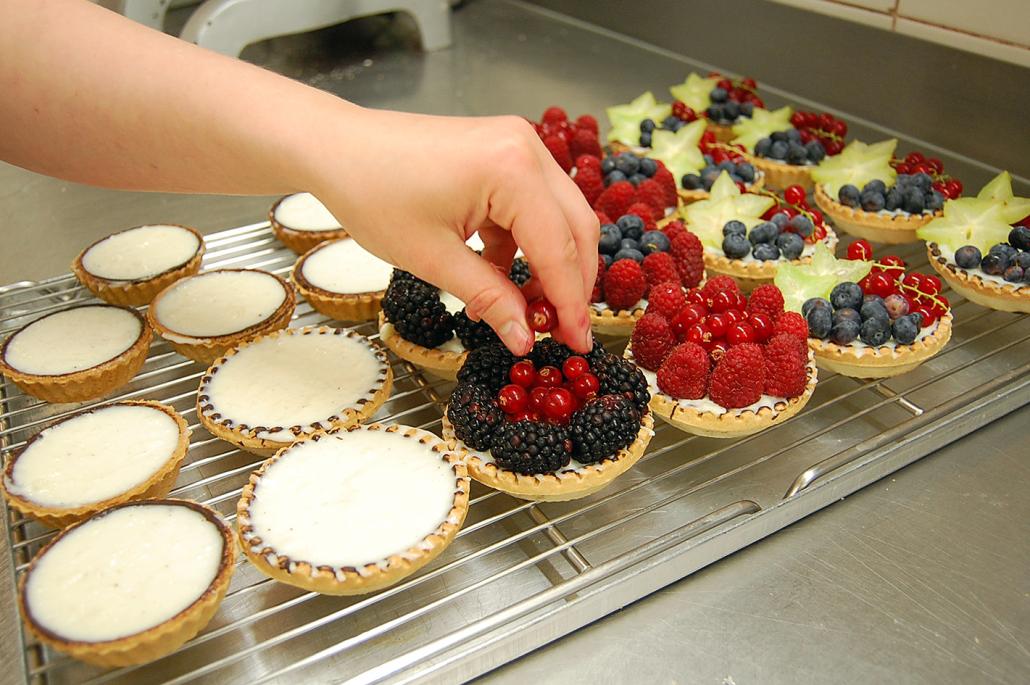 Liebevoll werden die Früchtetartes mit frischem Obst belegt