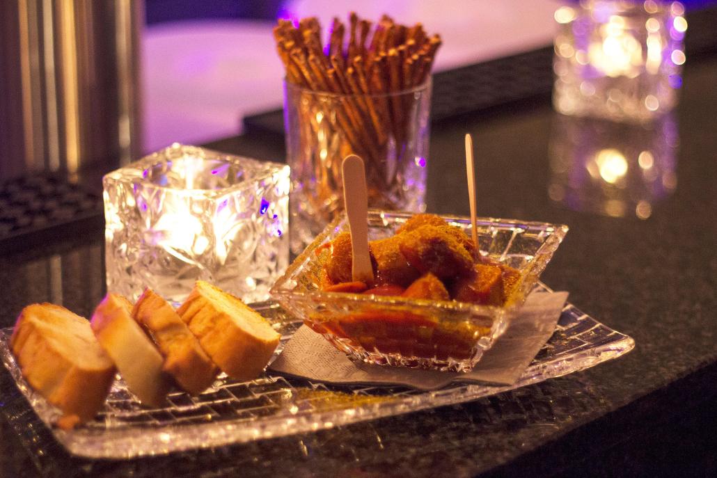 Zu den Drinks gibt es leckere Snackswie z. B. Currywurst von Extrawürste