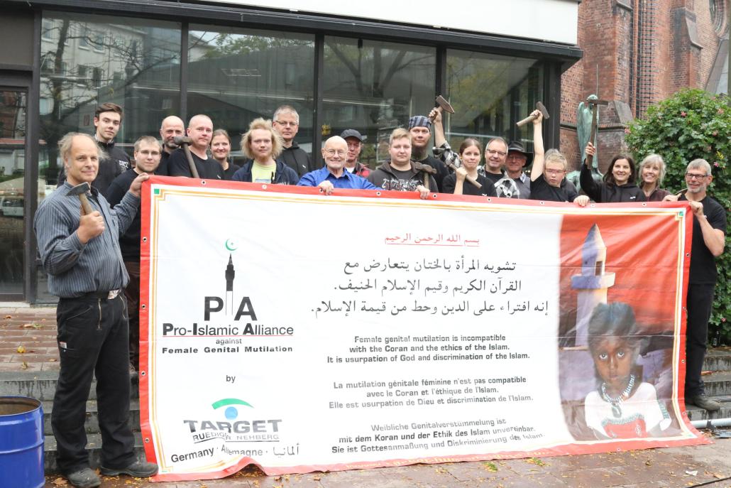 Die Schmiede um Organisator Heiko Voss (li.) präsentieren mit Rüdiger Nehberg (Mitte, blaues Hemd) und seiner Frau Annette (2. v. re.) ein Plakat, auf dem gemahnt wird, dass weibliche Genitalverstümmelung mit dem Koran unvereinbar ist