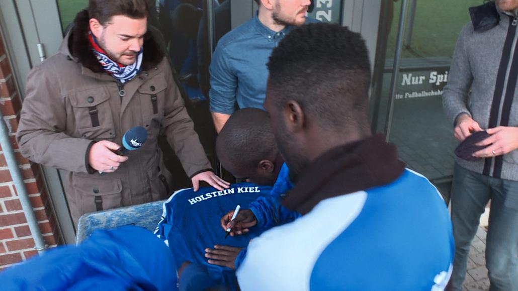 Fussballspieler Amara Conde (Mitte) unterschreibt auf dem Trikot