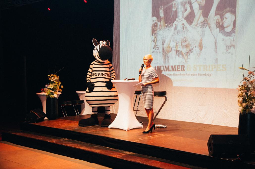 Anett Sattler moderiert regelmäßig Events. Hier führt sie beim großen Summer & Stripes Event des THW Kiel, Autohaus Süverkrüp und falkemedia durch den Abend