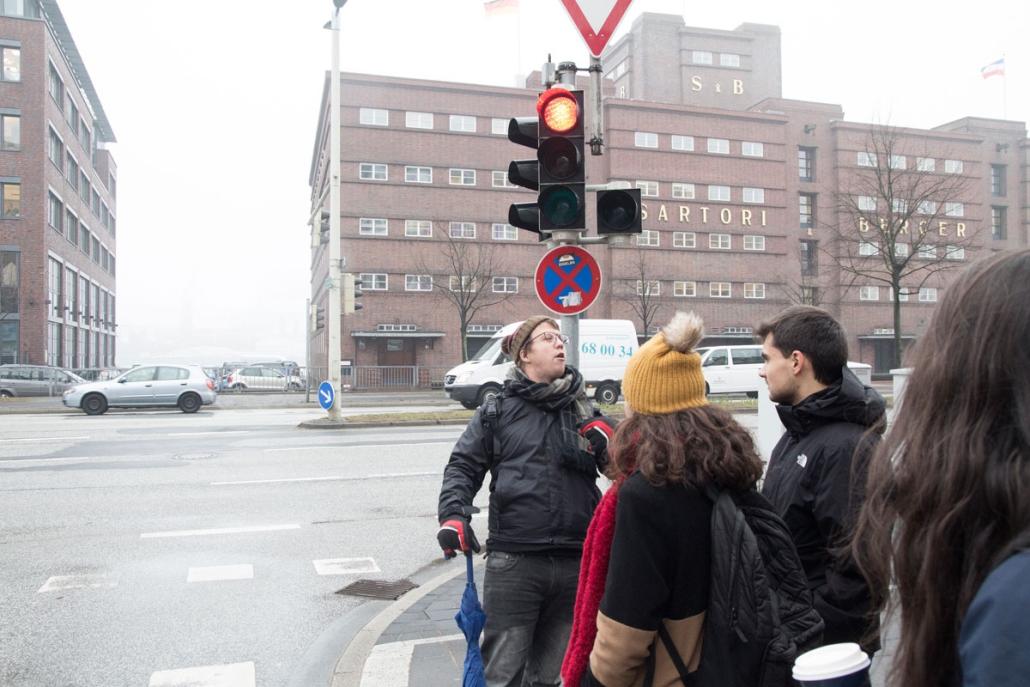 Kirk (li.) erklärt den Erasmus-Studenten, wie wichtig es in Deutschland ist, an der Ampel auf Grün zu warten