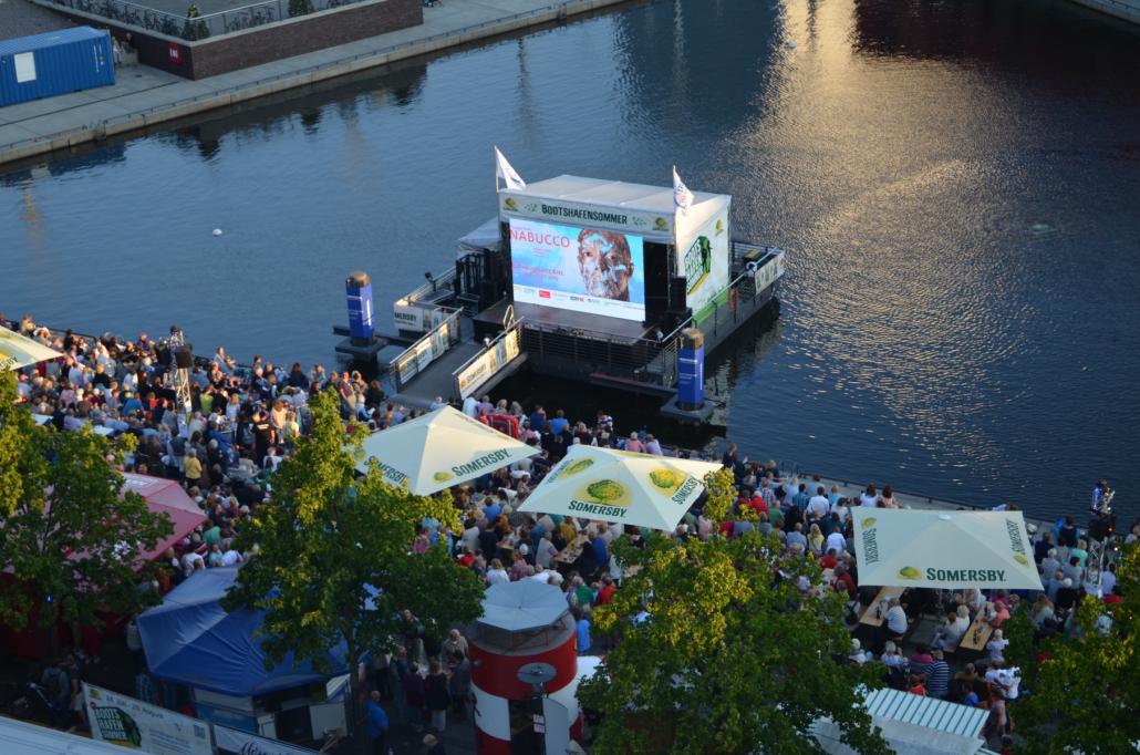 An vielen öffentlichen Orten kann man die Premiere des Sommertheaters verfolgen – so wie hier am Bootshafen