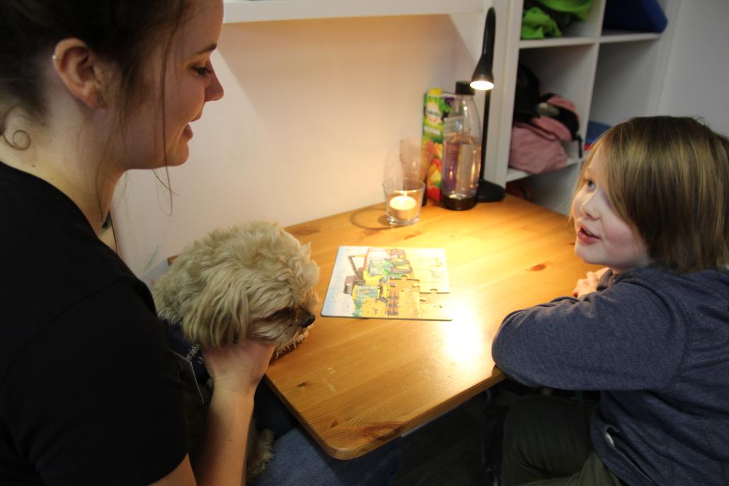 Ergotherapeutin Julia Rathjen mit Therapiehund „Pommes“ und Sam beim Puzzeln