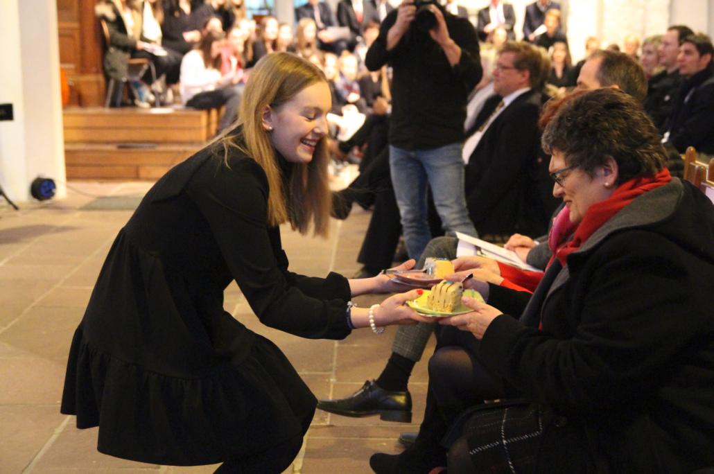 Schülersprecherin Greta Balow überreicht Bürgermeisterin Renate Treutel das symbolische Stück Geburtstagstorte