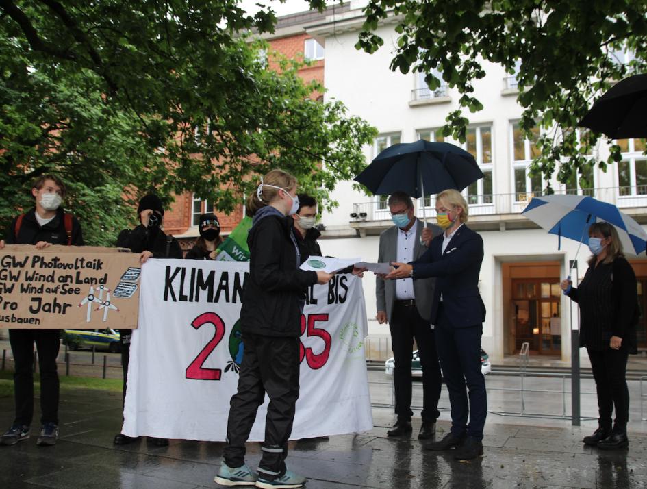 Dennys Bornhöft (FDP, 2. v. r.) nimmt das Schriftstück von Klima-Aktivistin Dorothea Lätzel entgegen.