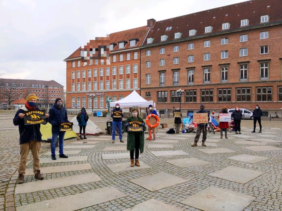 Auf dem Kieler Rathausplatz halten die Aktivist*innen der Gruppe „Sicherer Hafen Kiel“ eine Mahnwache für Geflüchtete ab