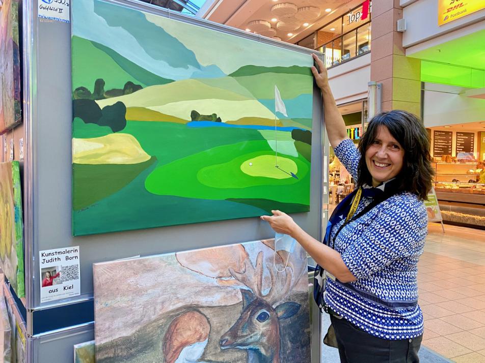 Judith Born präsentiert ihr Gemälde „Golfplatz“ in der Ausstellung