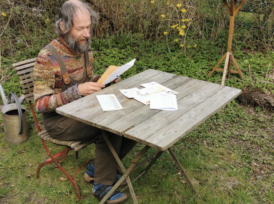 Chistian Kuhtz liest in seinem Garten in den Briefen, die er aus fernen Teilen der Erde bekommen hat.