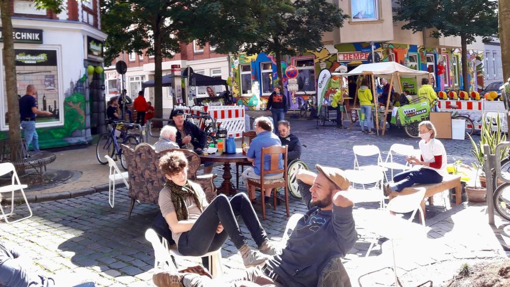 2020 startete in Gaarden mit dem 1. Kieler Parklet Tag bereits ein ähnlicher Versuch samt Kreuzungssperrung, Kundgebung und gemütlichem Beisammensein