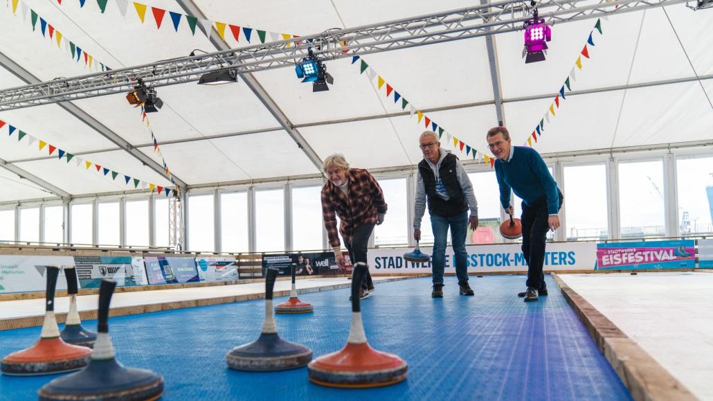 vl: Uwe Wanger (Kiel-Marketing), Thomas Hein (interevent) und Frank Meier ( Stadtwerke Kiel) probieren sich im Eisstockschießen auf den Kunststoffbahnen.