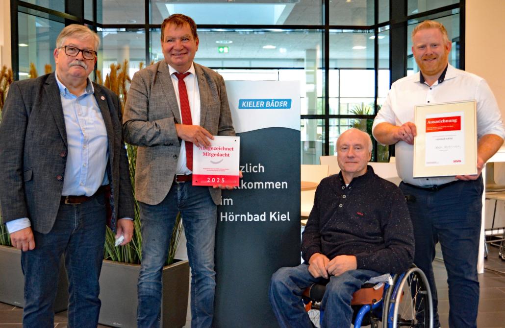 SoVD-Landesvorsitzender Alfred Bornhalm (links) und Barrierefreiheit-Experte Mario Eggers (im Rollstuhl) überreichten Stadtrat Gerwin Stöcken (Zweiter von links) und Schwimmbäder-Werkleiter Christian Jacobsen (rechts) Gütesiegel und Urkunde.