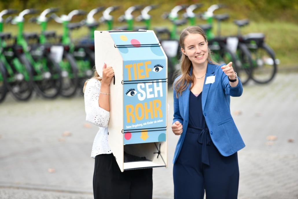 Marlene Lorenzen vom mobiliteam by NAH.SH  zeigt das Tiefsehrohr, mit dem Erwachsene die Perspektive von Kindern einnehmen können.