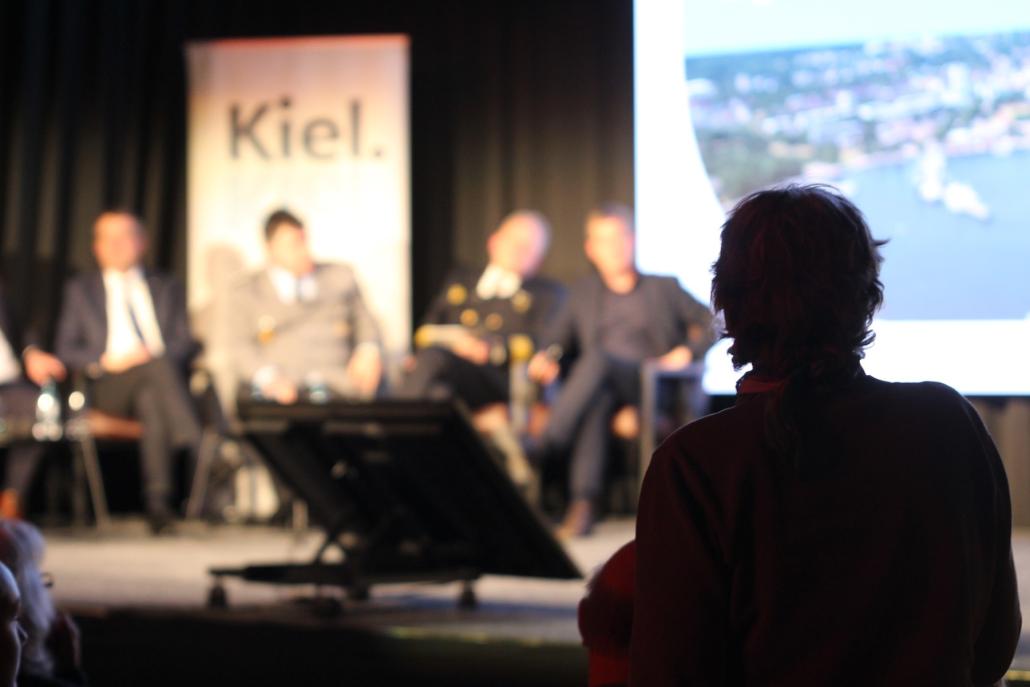 Die Sorge im Nacken: Eine Bürgerin blickt auf die Verantwortlichen auf dem Podium.